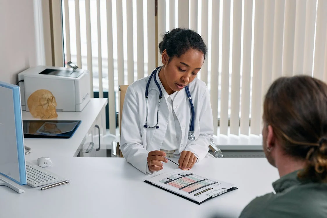 Picture of a patient and doctor sat at a desk having a conversation